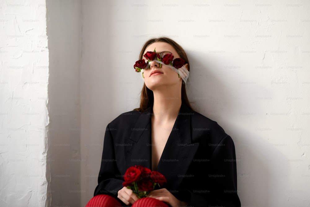 una mujer con chaqueta negra y medias rojas sosteniendo un ramo de rosas