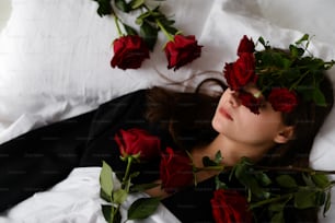 a woman laying on a bed with roses in her hair