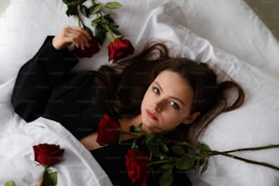 uma mulher deitada em uma cama com rosas vermelhas