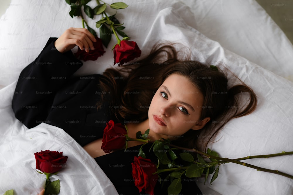 une femme allongée sur un lit avec des roses rouges