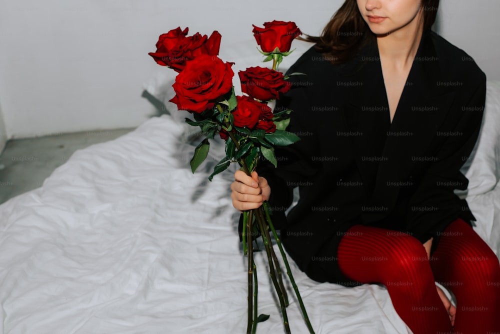 a woman sitting on a bed holding a bouquet of roses