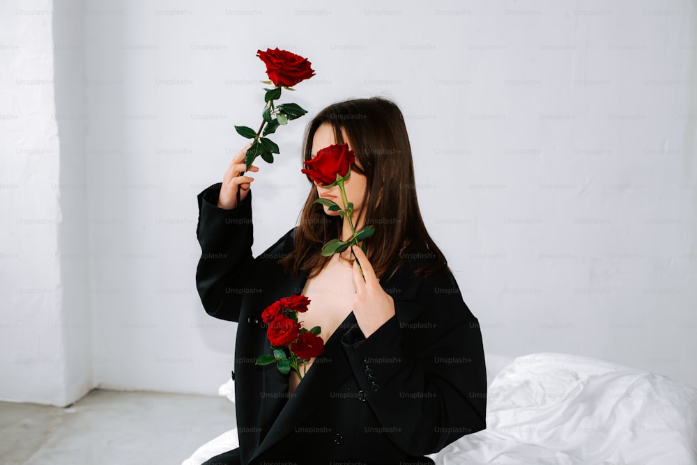 a woman sitting on a bed holding two roses