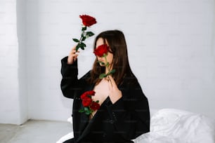 a woman sitting on a bed holding two roses