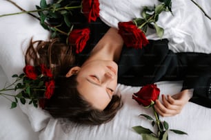 a woman laying on a bed with roses in her hair