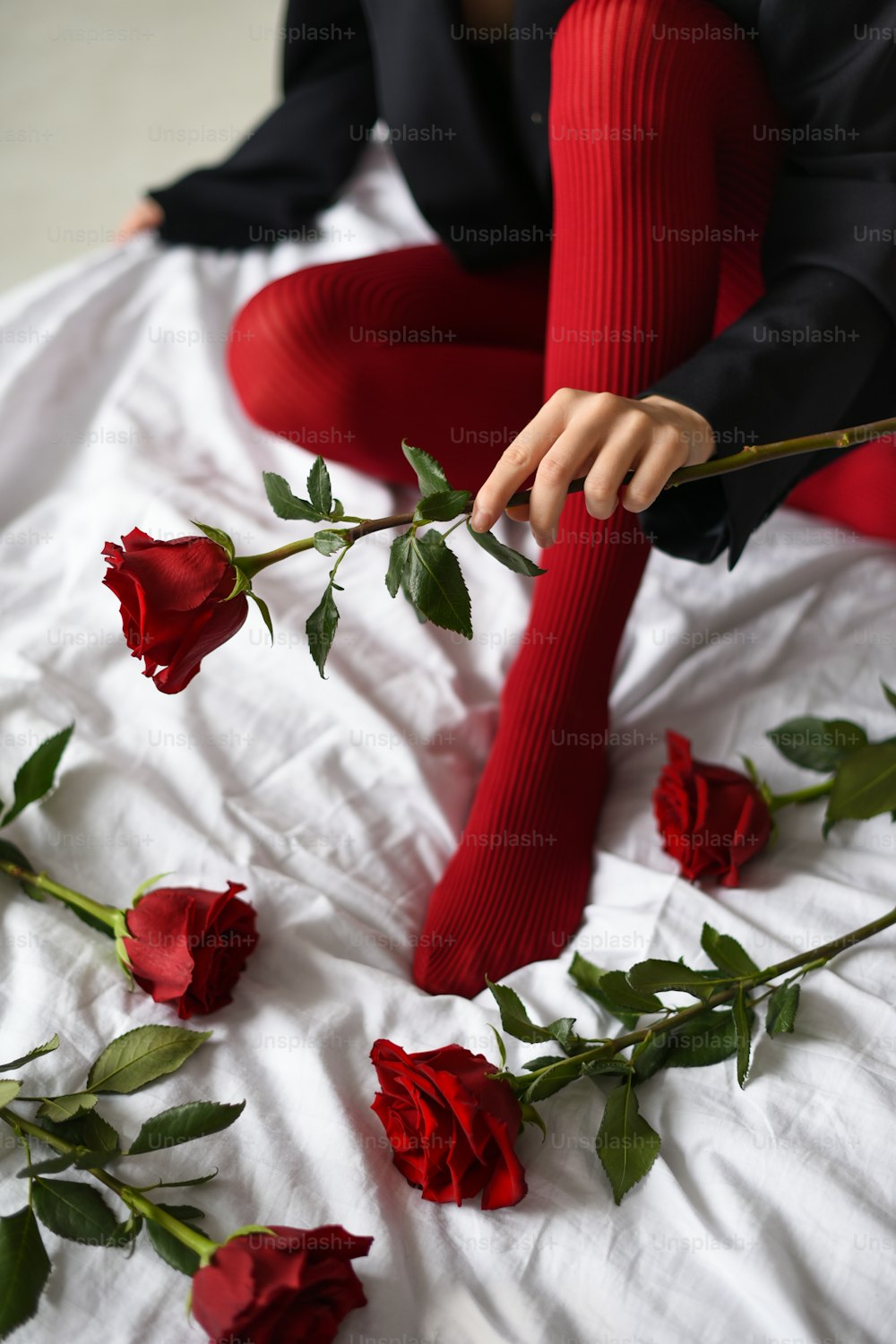 a woman sitting on a bed holding a rose