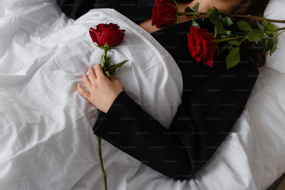 a woman laying on a bed with roses in her lap
