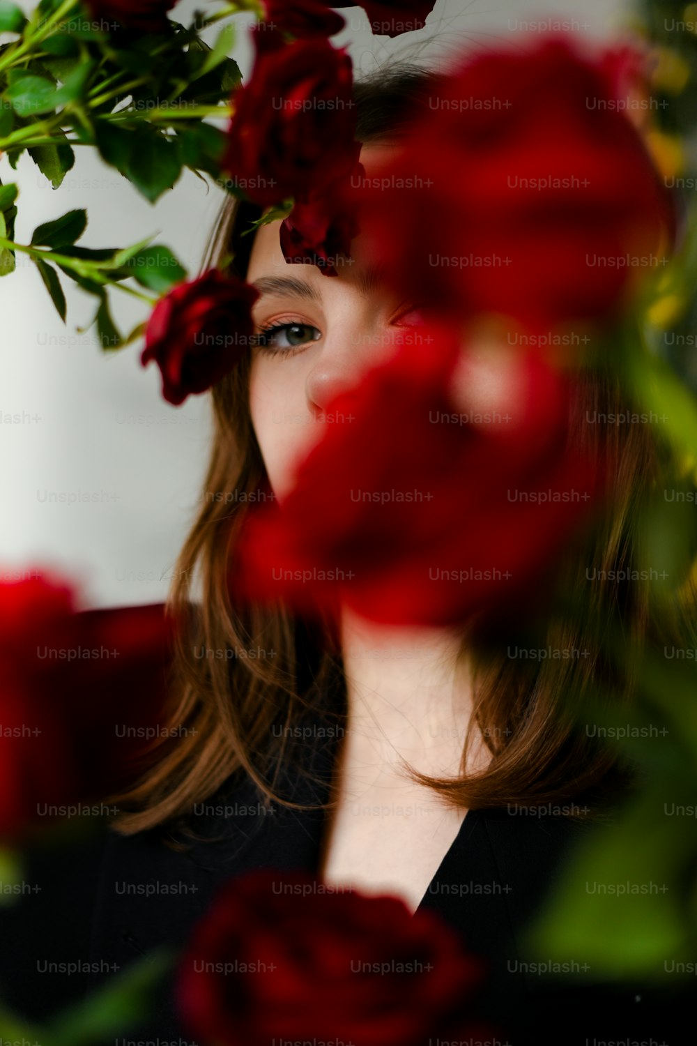 a woman with long hair and a black shirt is surrounded by red roses
