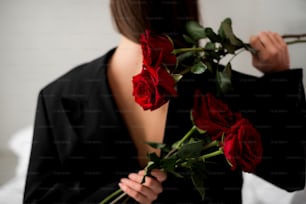 a woman in a black jacket holding a bouquet of roses