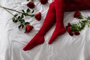 a woman laying on a bed with red roses