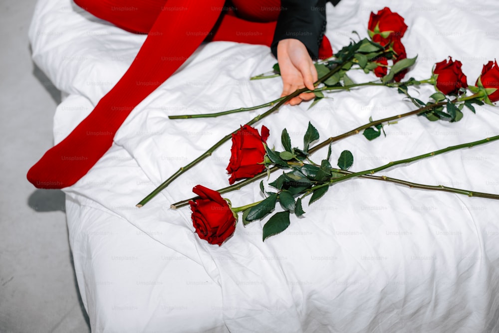 a woman laying on a bed with red roses