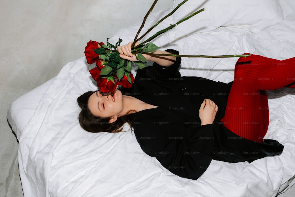 a woman laying on a bed with a bunch of roses on her head