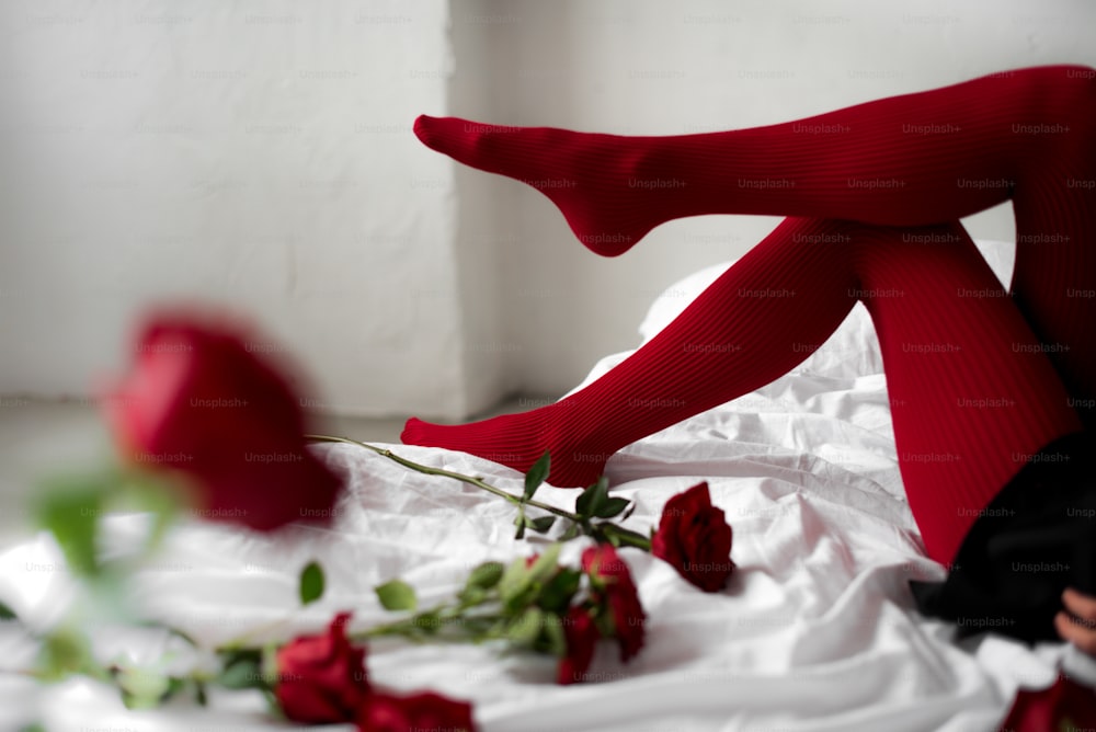 赤い薔薇の花が咲くベッドに横たわる女性