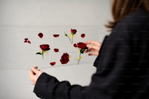 a woman holding a piece of glass with red roses on it