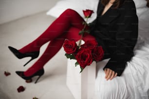 uma mulher sentada em uma cama segurando um buquê de rosas