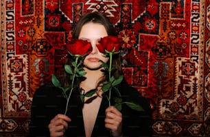 a woman holding two roses in front of her face