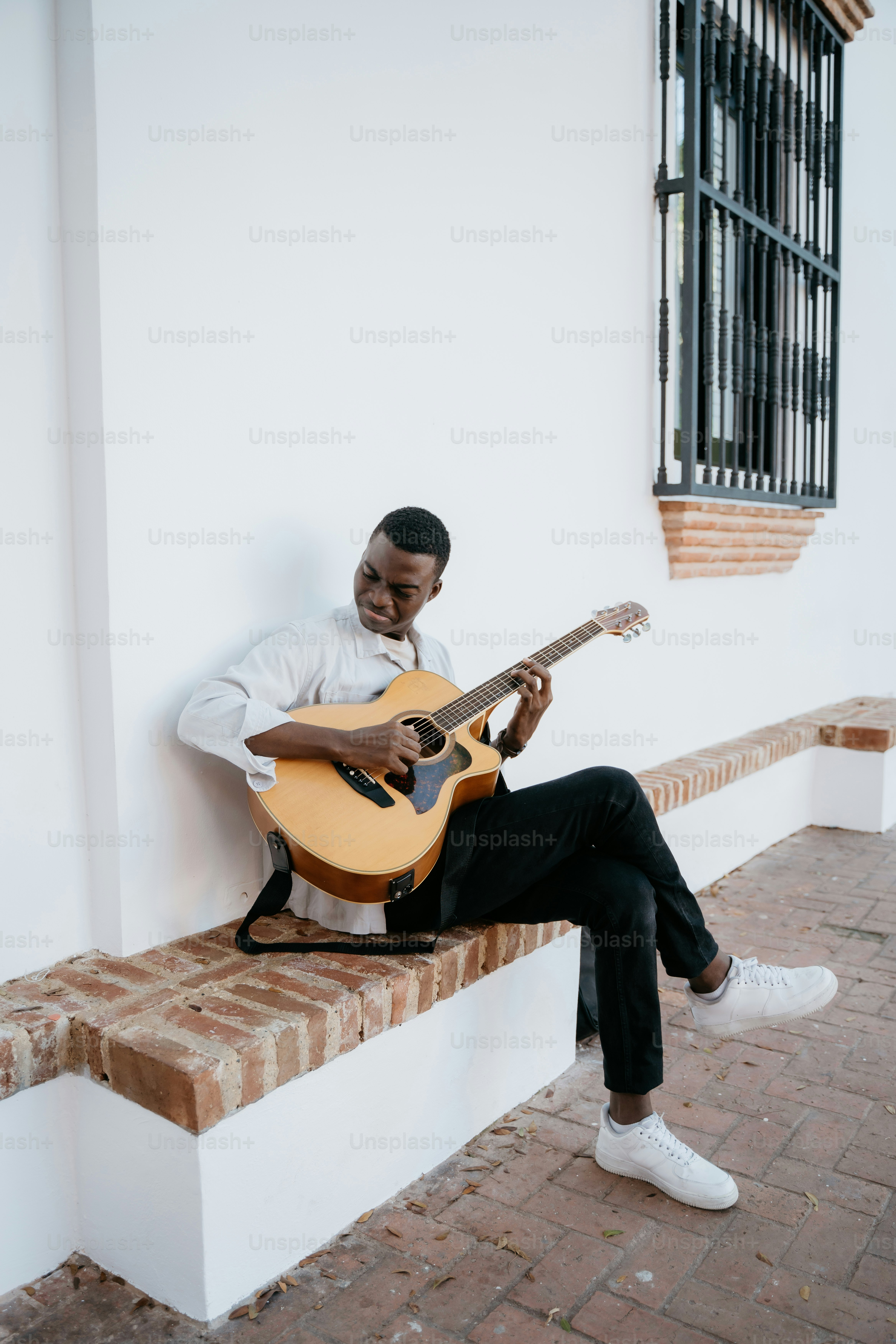 a man sitting on a bench playing a guitar