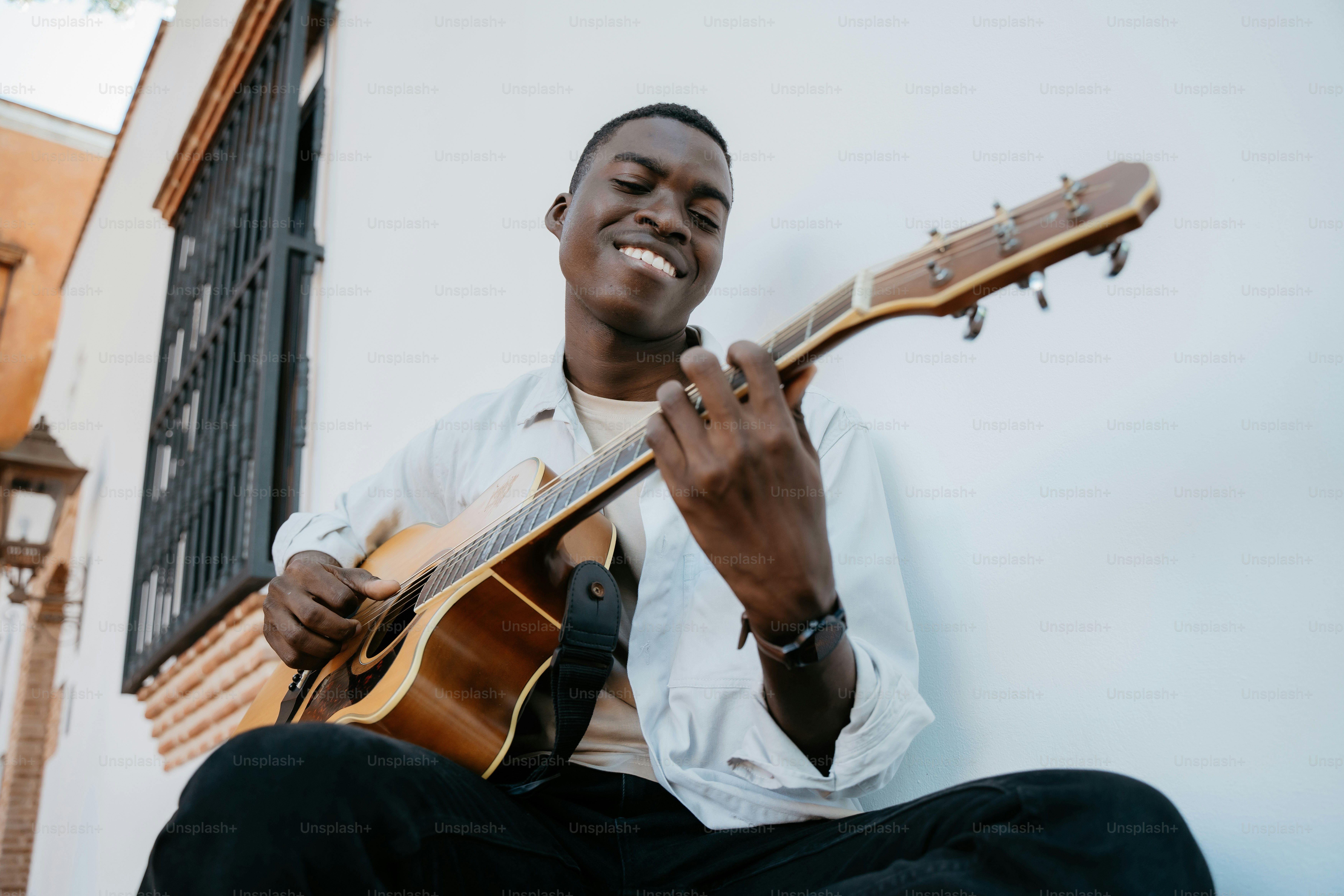 a man sitting on the ground playing a guitar