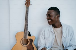 a man sitting next to a guitar smiling