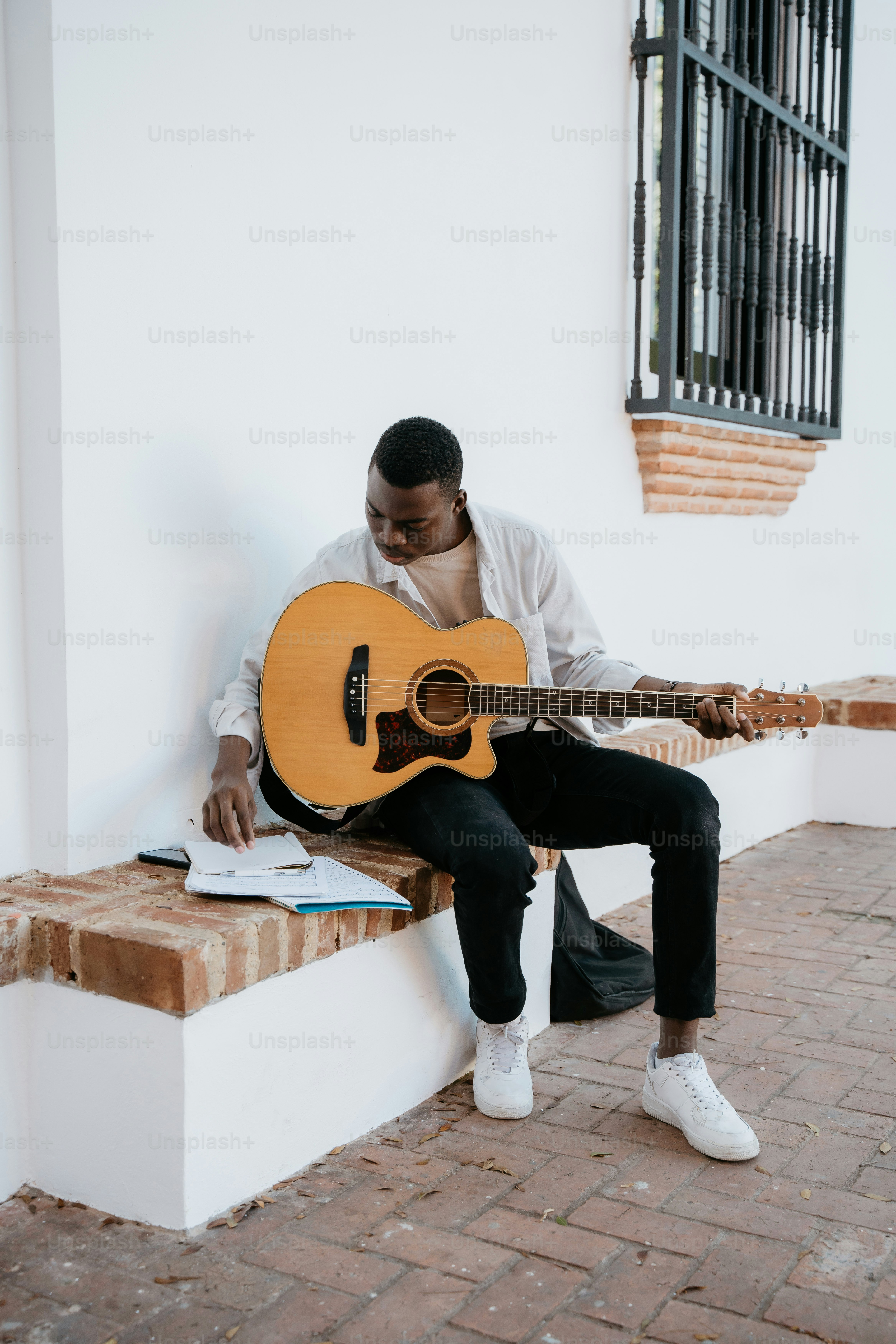a man sitting on a bench playing a guitar