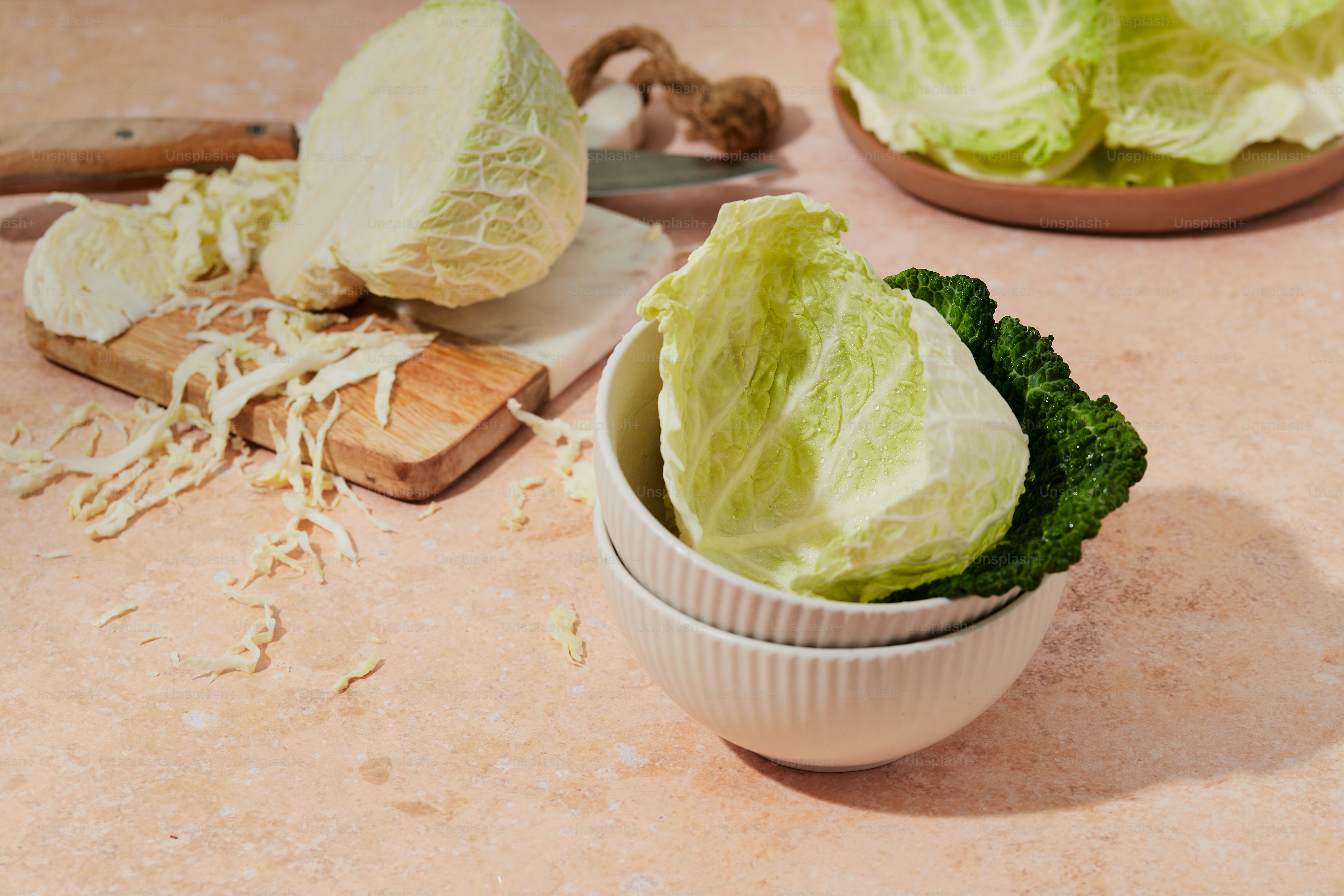 Foto Un bol lleno de lechuga junto a una tabla de cortar – Repollo ...