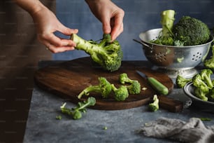 una persona che taglia i broccoli su un tagliere