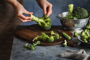 a person cutting broccoli on a cutting board