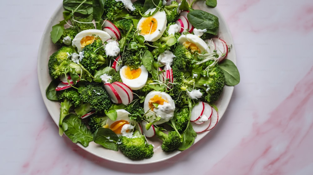 un plato blanco cubierto con brócoli y huevos duros