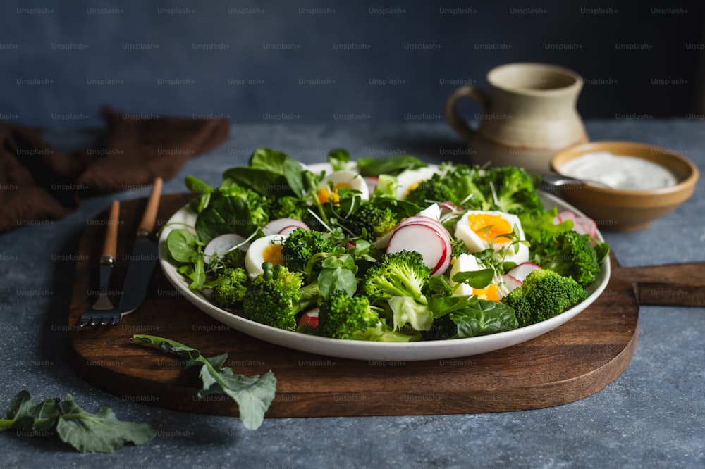 a plate of broccoli, radishes, and eggs on a wooden