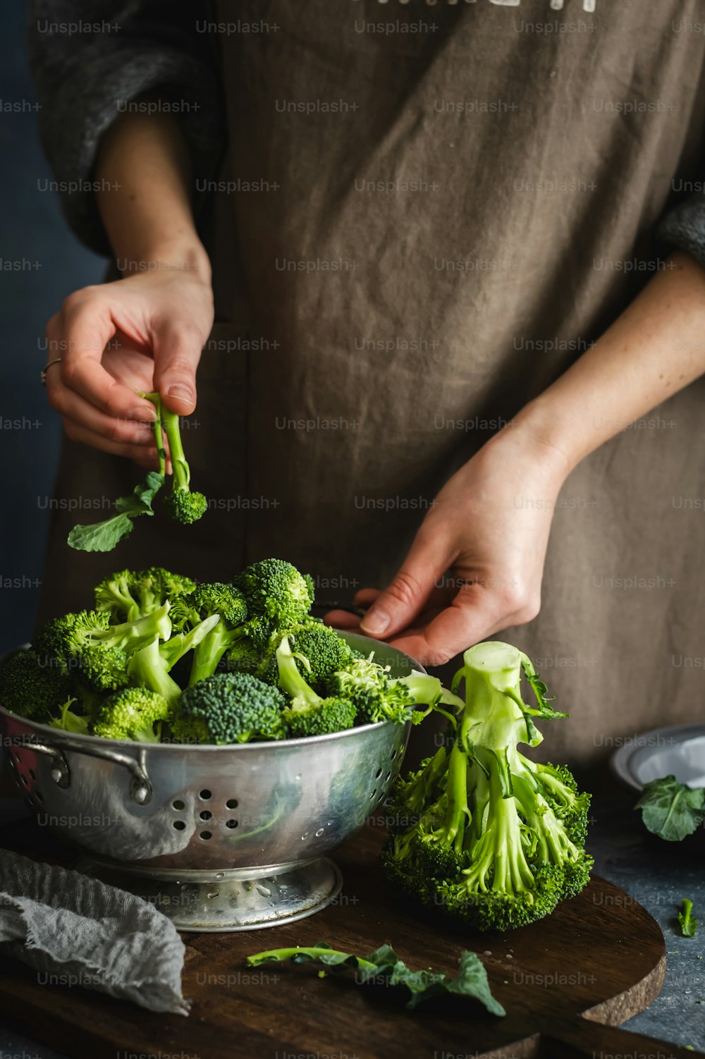 a person in an apron is cutting broccoli in a bowl