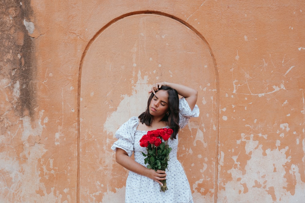 a woman in a white dress holding a bouquet of roses