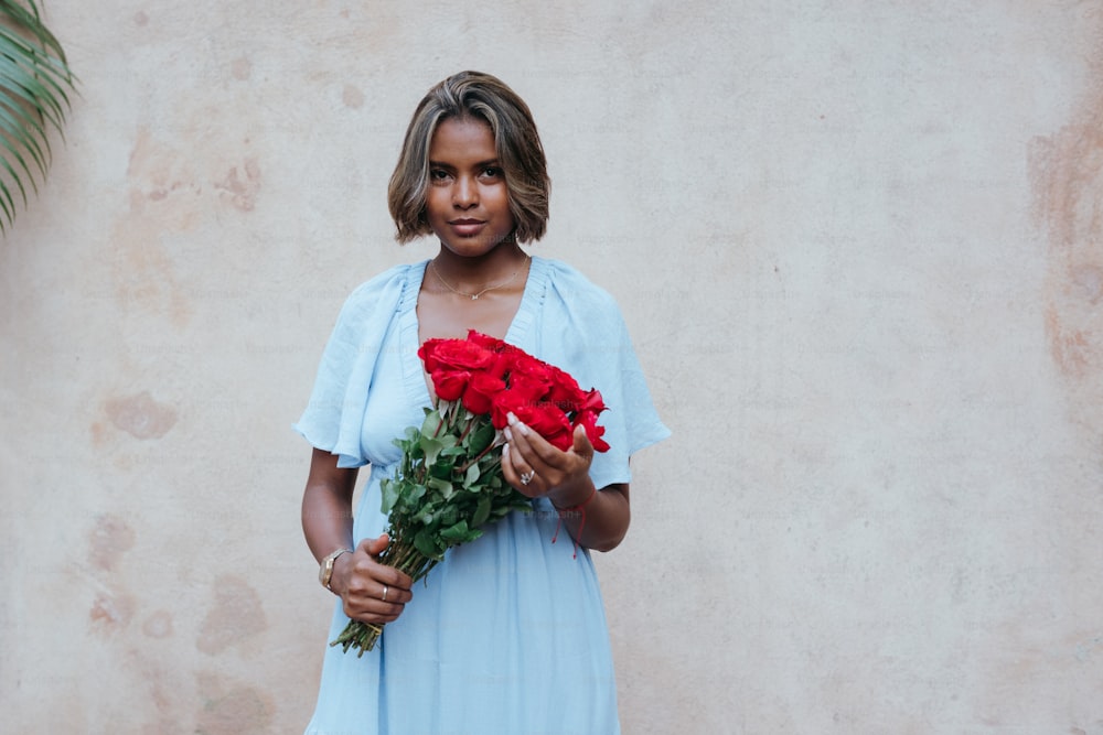 une femme en robe bleue tenant un bouquet de fleurs