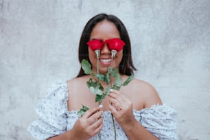 uma mulher usando óculos vermelhos segurando uma rosa