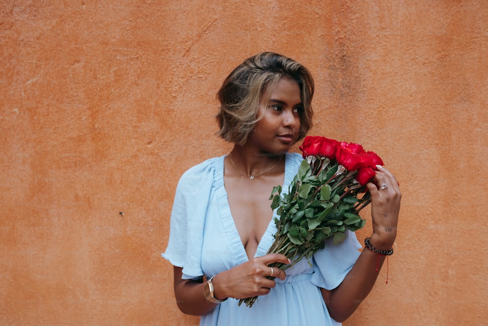 a woman in a blue dress holding a bouquet of roses