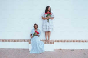 zwei Frauen stehen nebeneinander und halten Rosen in den Händen
