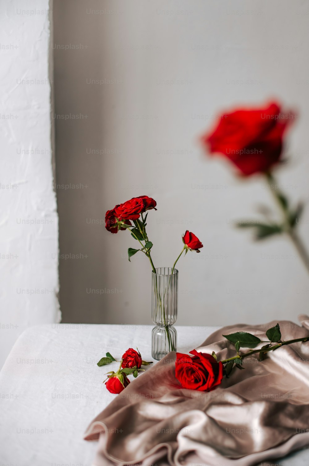 tres rosas rojas en un jarrón sobre una mesa
