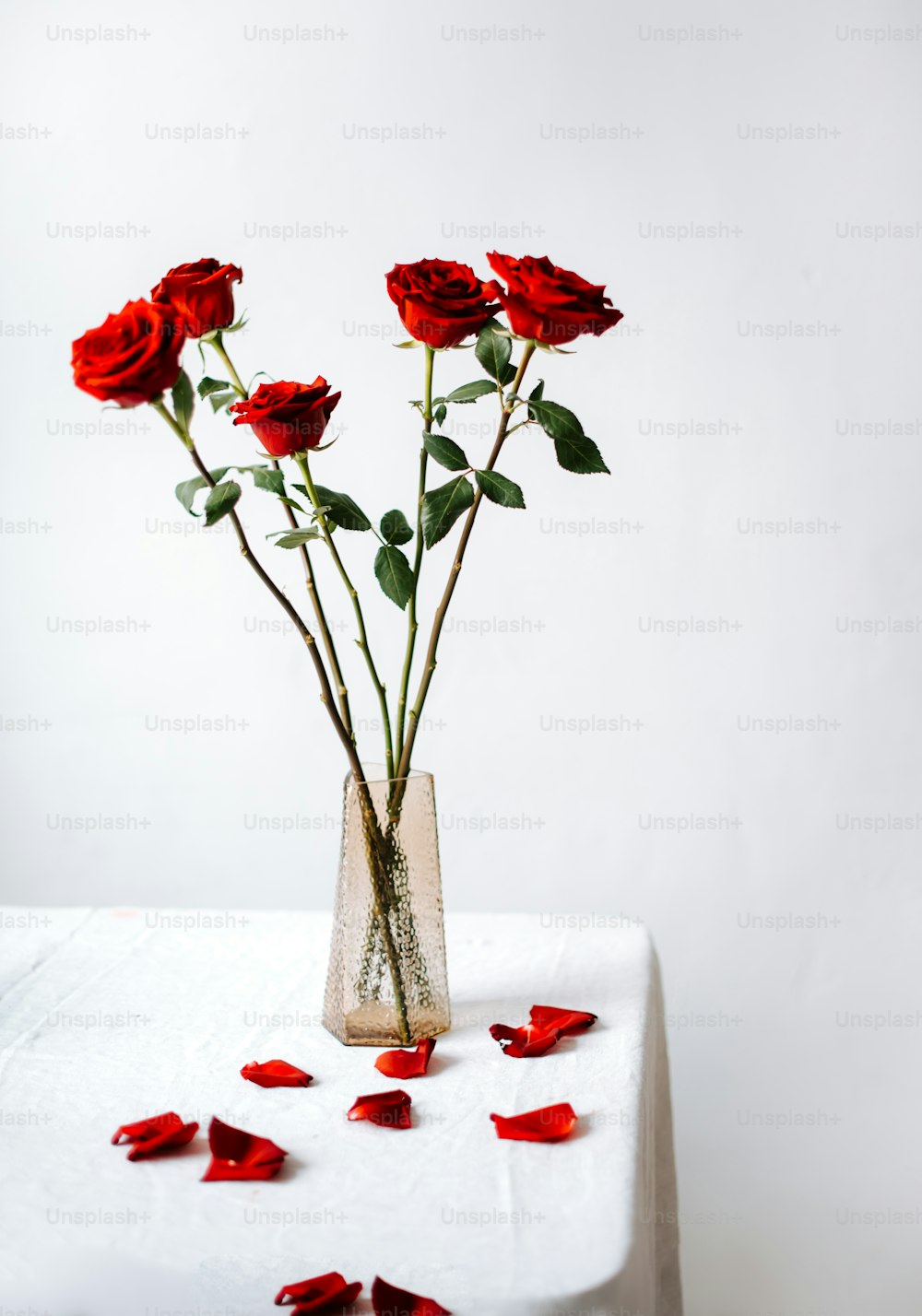 un jarrón lleno de rosas rojas encima de una mesa