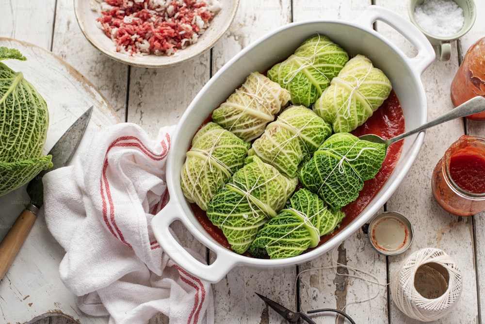 a white dish filled with cabbage covered in sauce