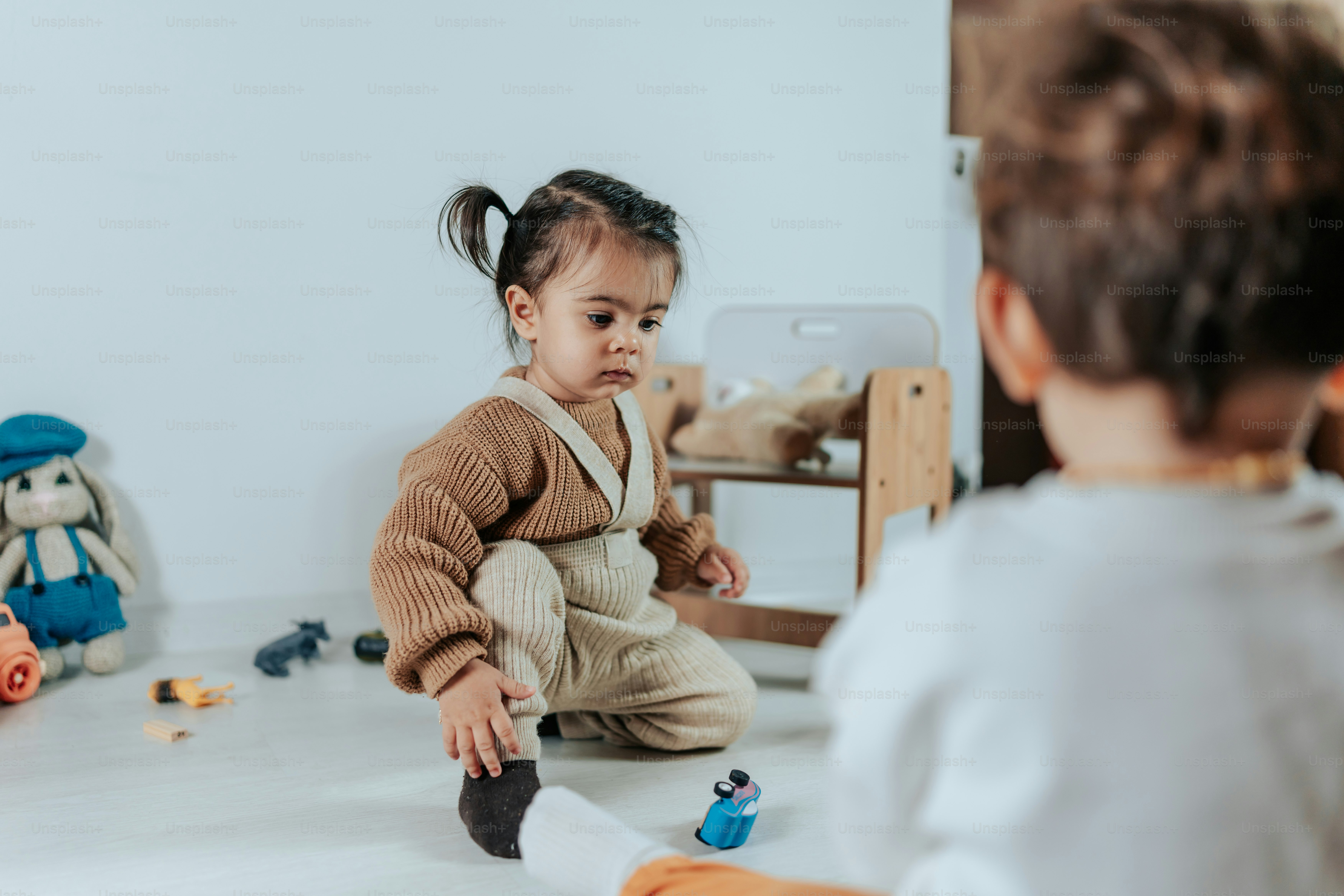 a little girl sitting on the floor playing with a toy