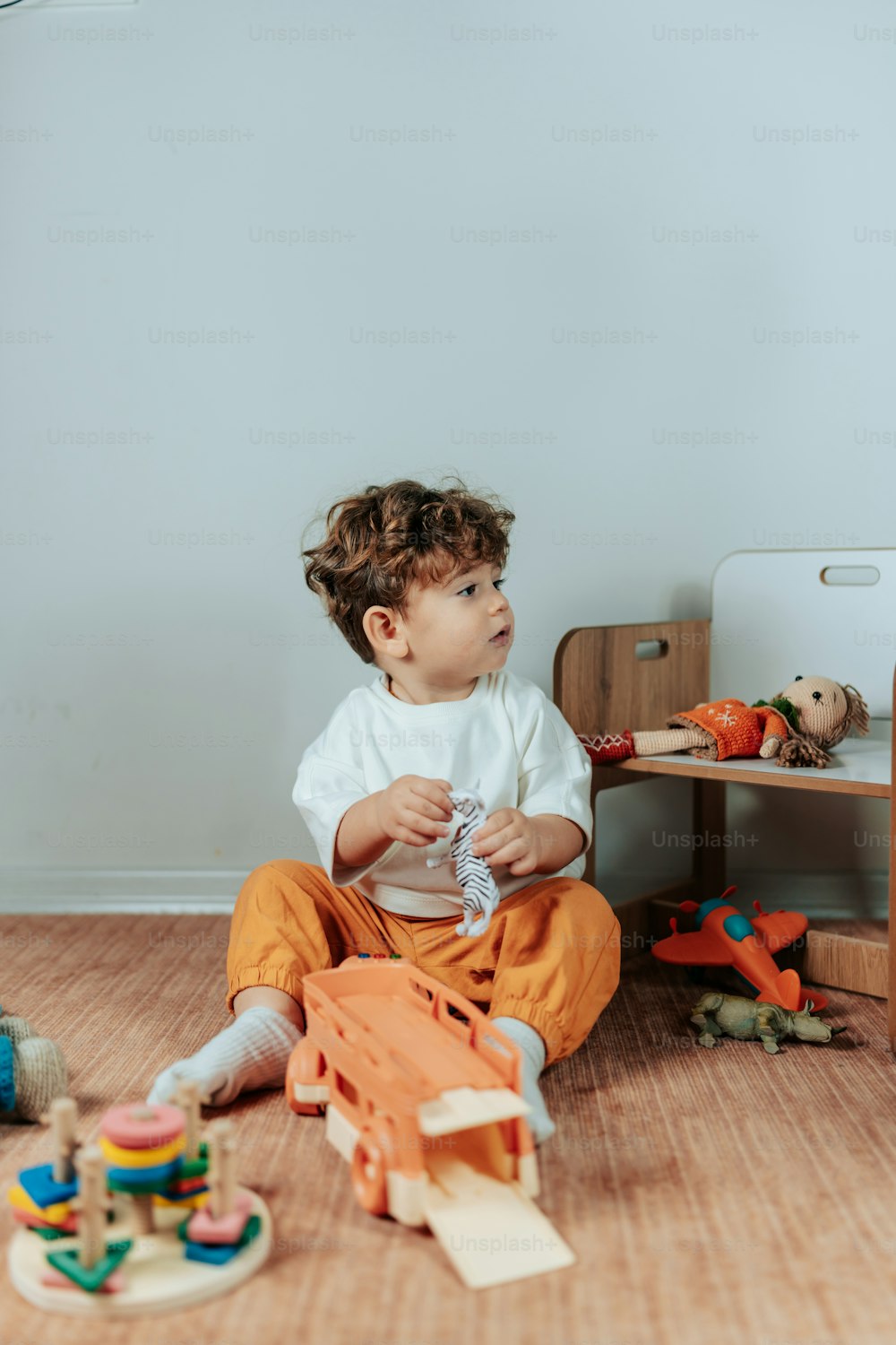 un ragazzino seduto sul pavimento che gioca con i giocattoli