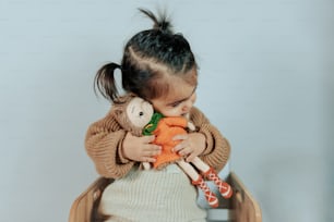 a little girl sitting in a chair holding a stuffed animal