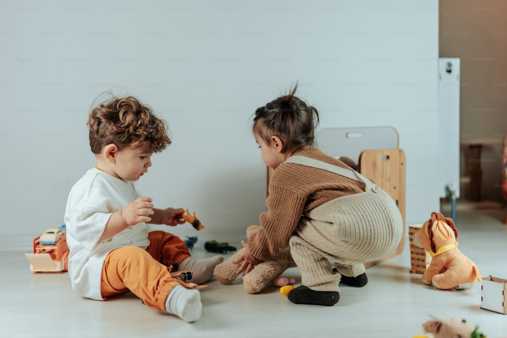 Dos niños pequeños jugando con juguetes en el suelo