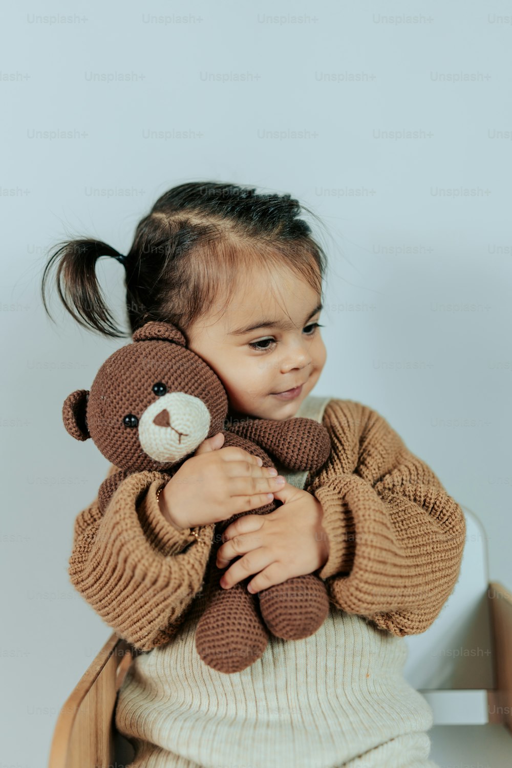 ein kleines Mädchen, das einen Teddybären auf dem Arm hält