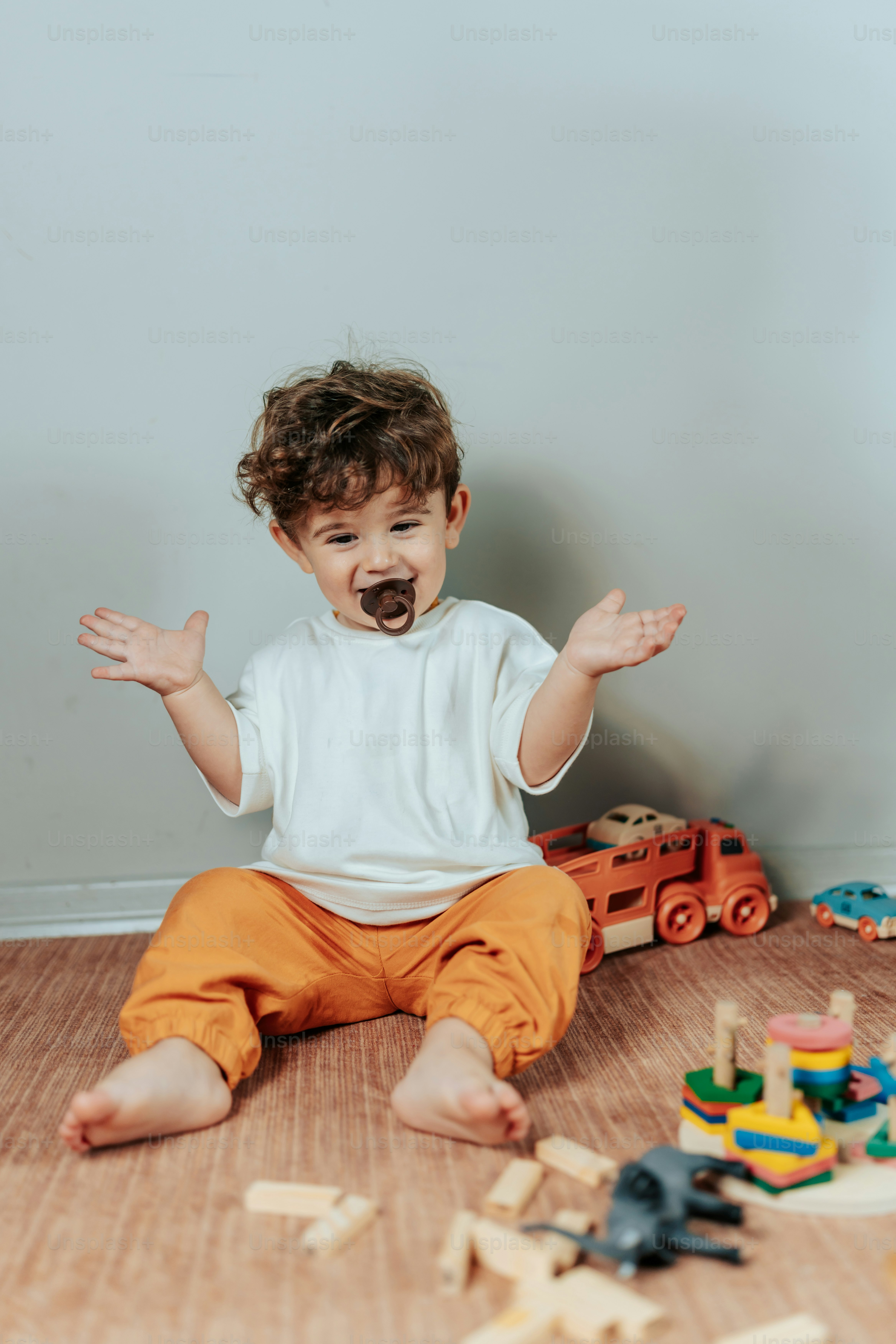 両手を宙に浮かべて床に座っている幼児