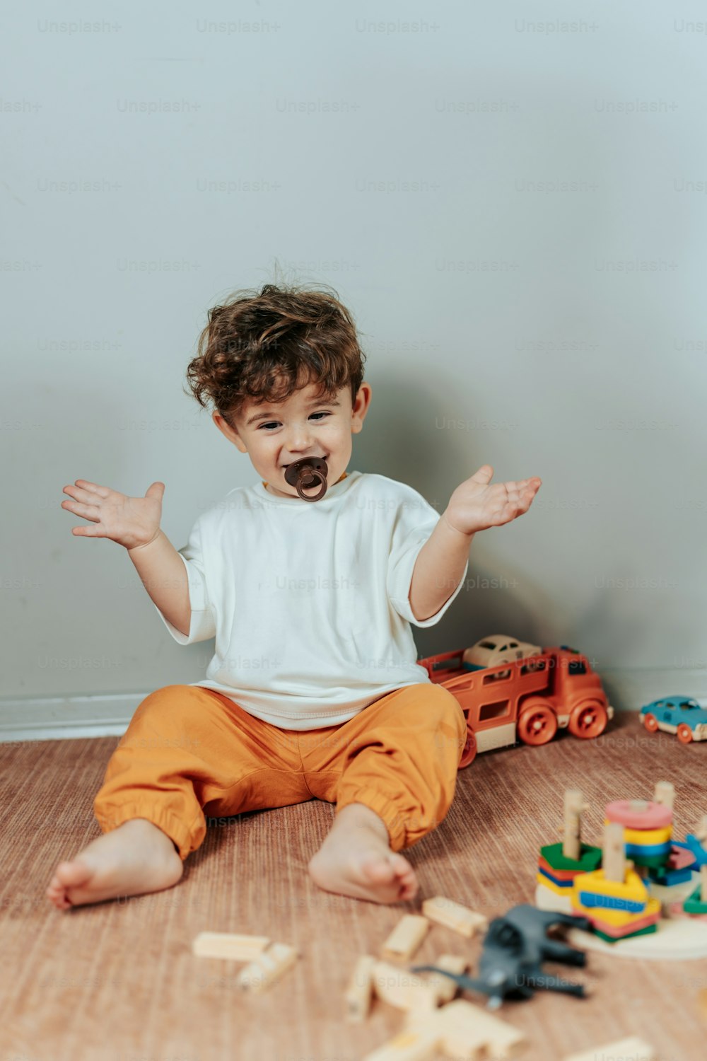 a toddler sitting on the floor with his hands in the air