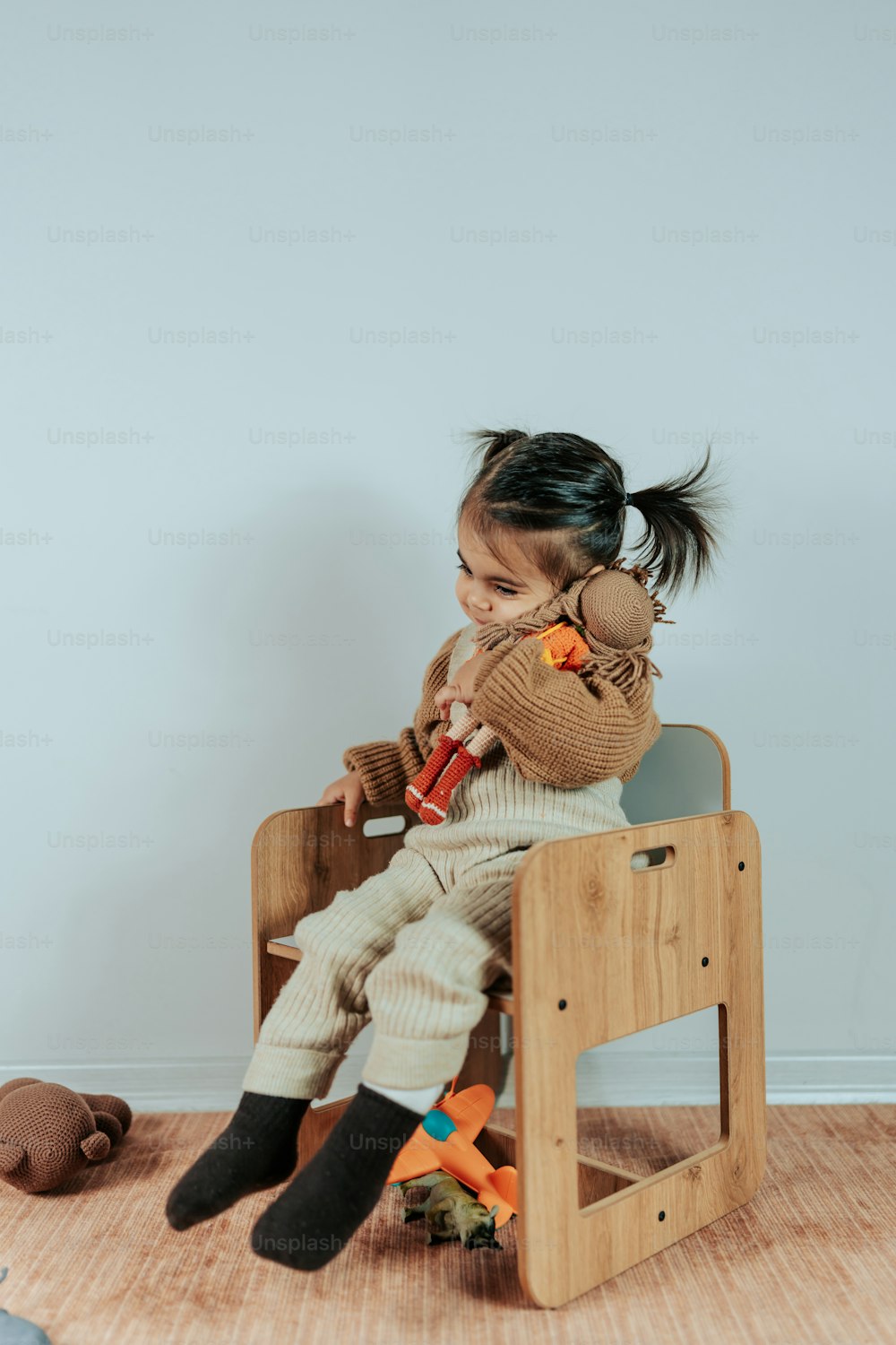 una niña sentada en una silla de madera