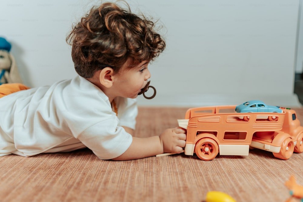 um bebê brincando com um caminhão de brinquedo no chão