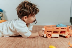 ein Baby, das mit einem Spielzeug-LKW auf dem Boden spielt