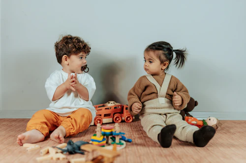 Deux enfants assis par terre jouant avec des jouets