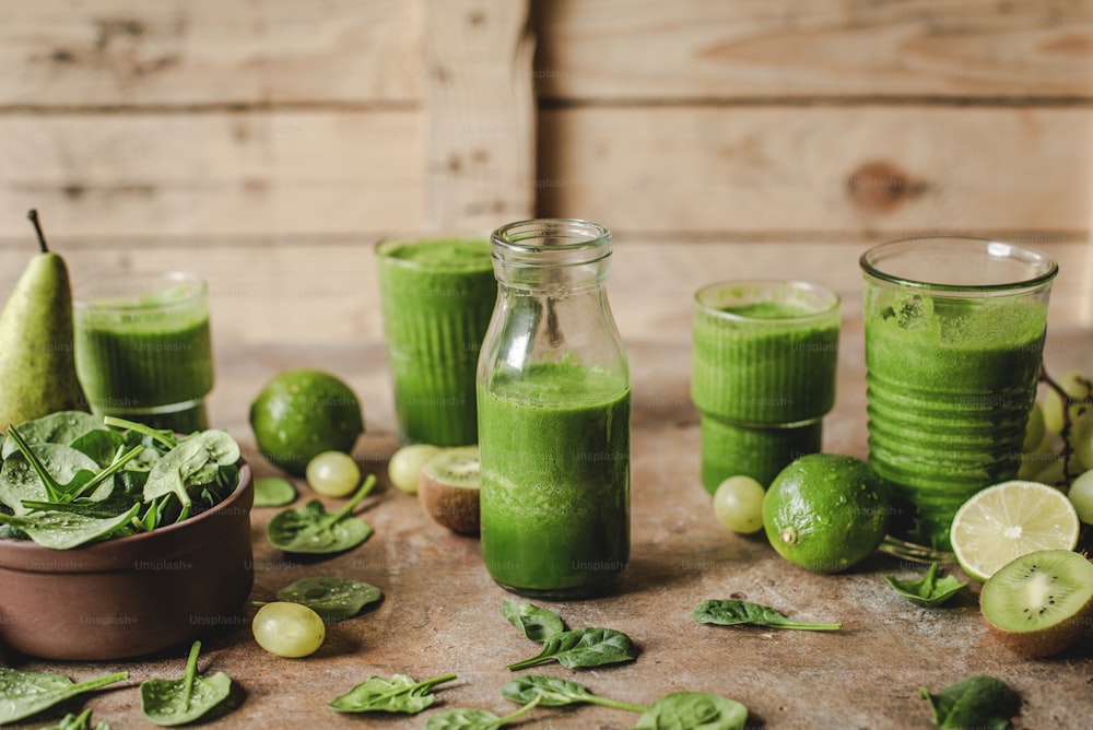 a table topped with glasses filled with green smoothies