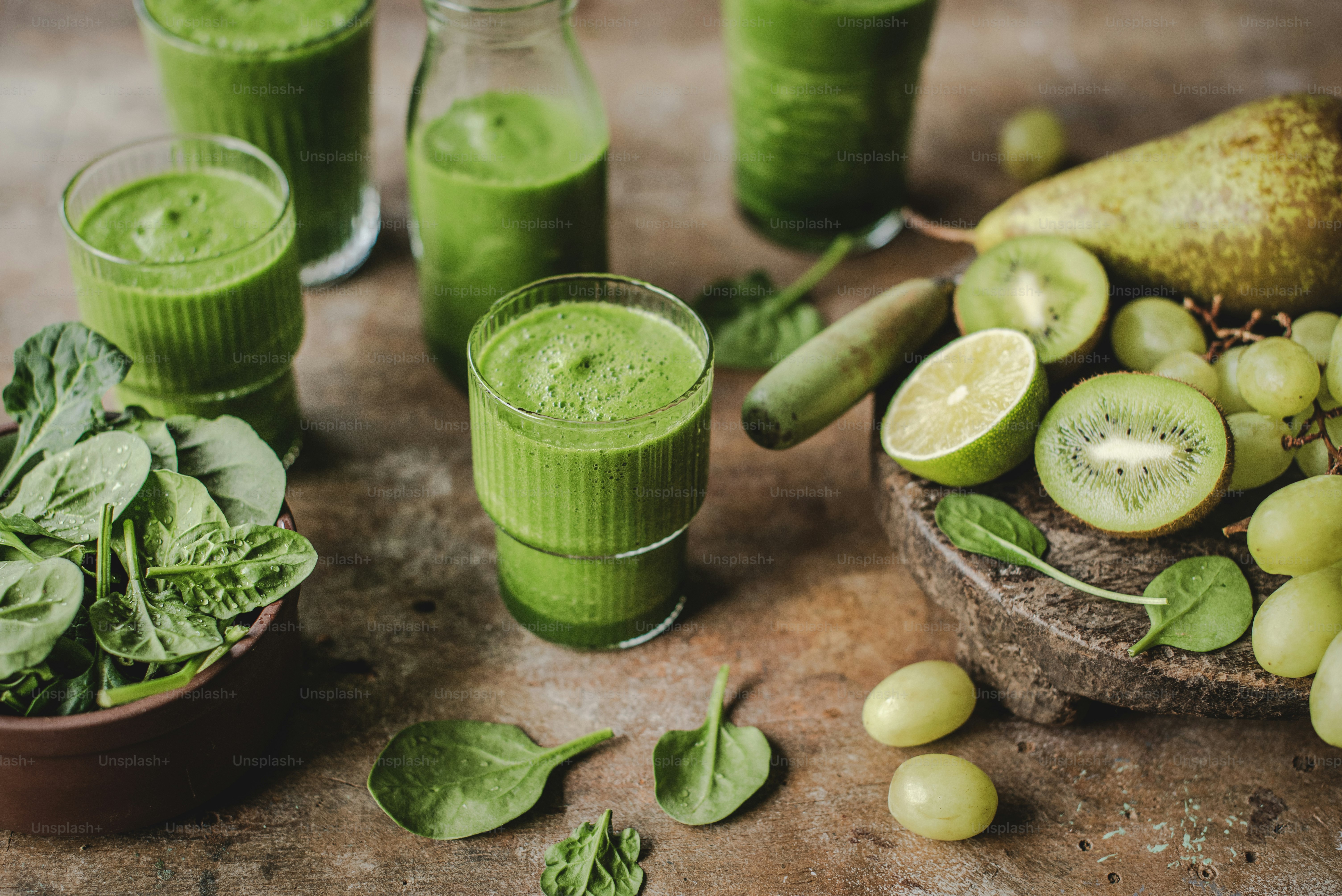 a table topped with glasses filled with green smoothies